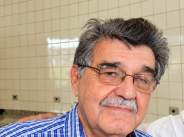 Retrato do jornalista João Natalício de Oliveira, de Ponta Porã, com óculos e camisa azul xadrez; imagem aprimorada digitalmente
